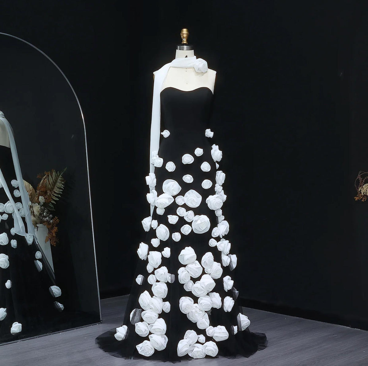 Black trumpet gown with sweetheart neckline and white 3D floral tulle appliqués on a mannequin.