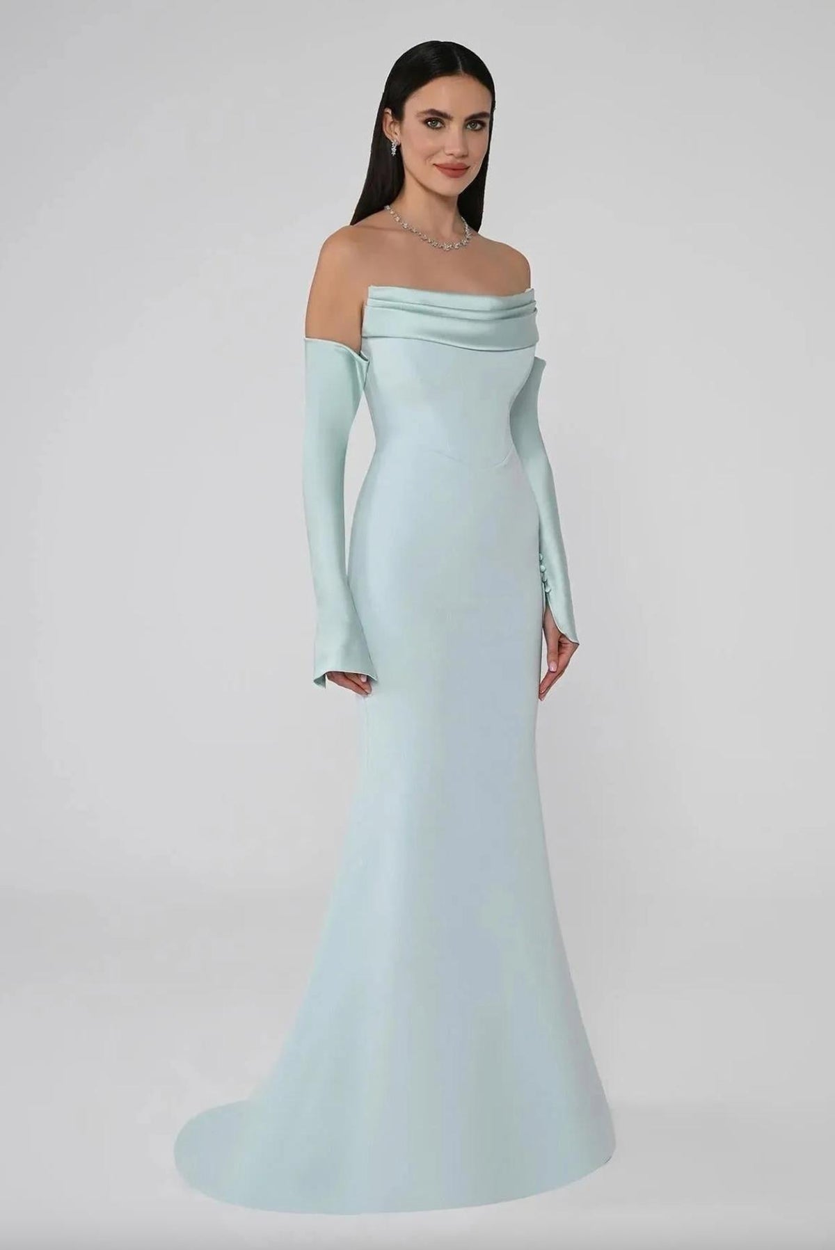 Mint green satin mermaid evening gown with off-the-shoulder neckline, long sleeves, and button accents.
