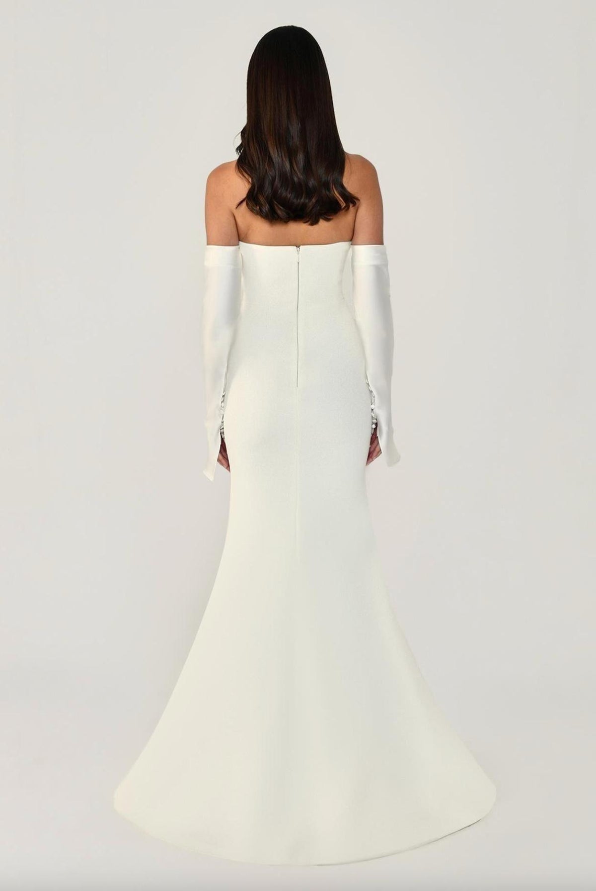 Back view of a white strapless mermaid evening gown with matching satin opera gloves and button details.