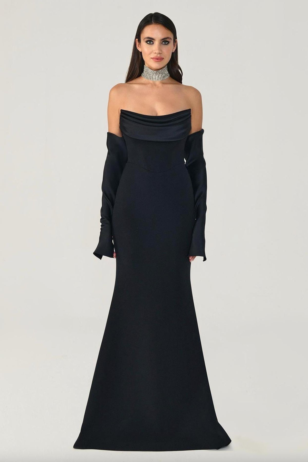Black strapless mermaid evening gown with a draped bodice, matching long gloves, and a sleek floor-length silhouette.