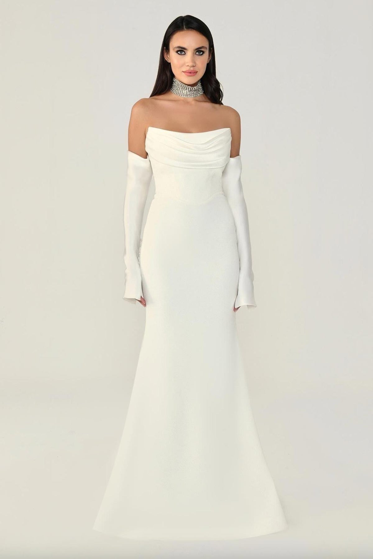 White strapless mermaid evening gown with pleated bodice, satin opera gloves, and a sleek floor-length silhouette.