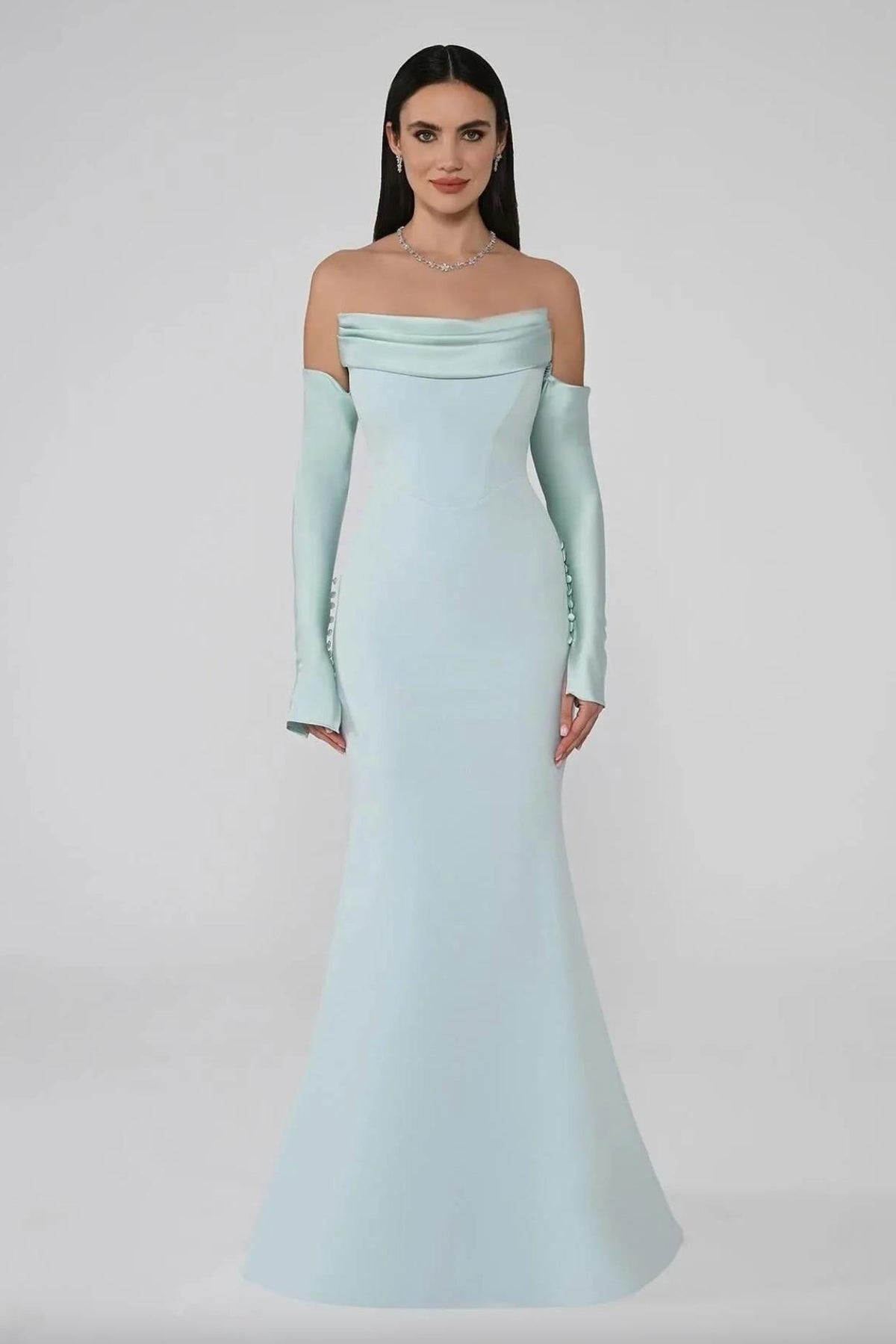 Mint green satin mermaid evening gown with strapless neckline, pleated bodice, and long sleeves with button details.