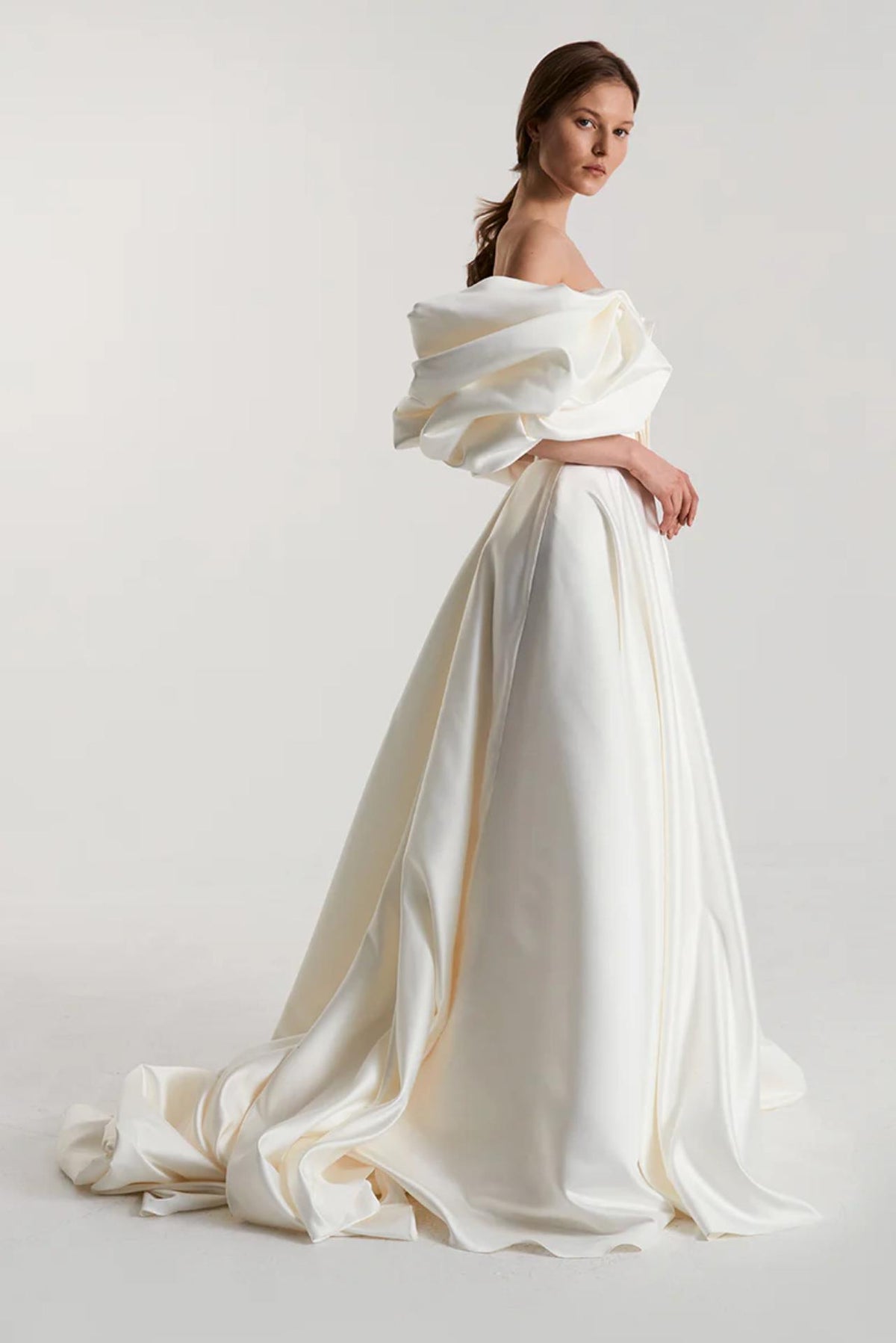 Off-shoulder white satin A-line gown with voluminous pleated bodice and elegant floor-length skirt.