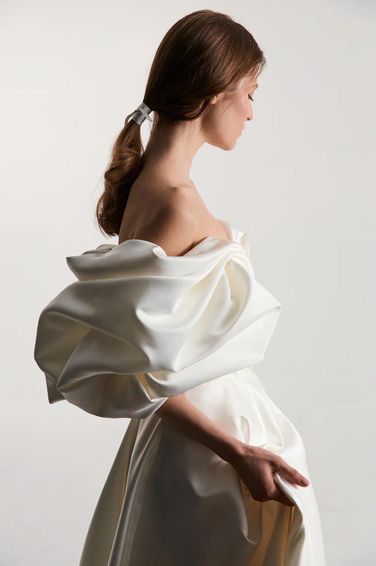 Woman wearing a white off-shoulder satin A-line gown with voluminous pleated sleeves and a vintage-inspired design.
