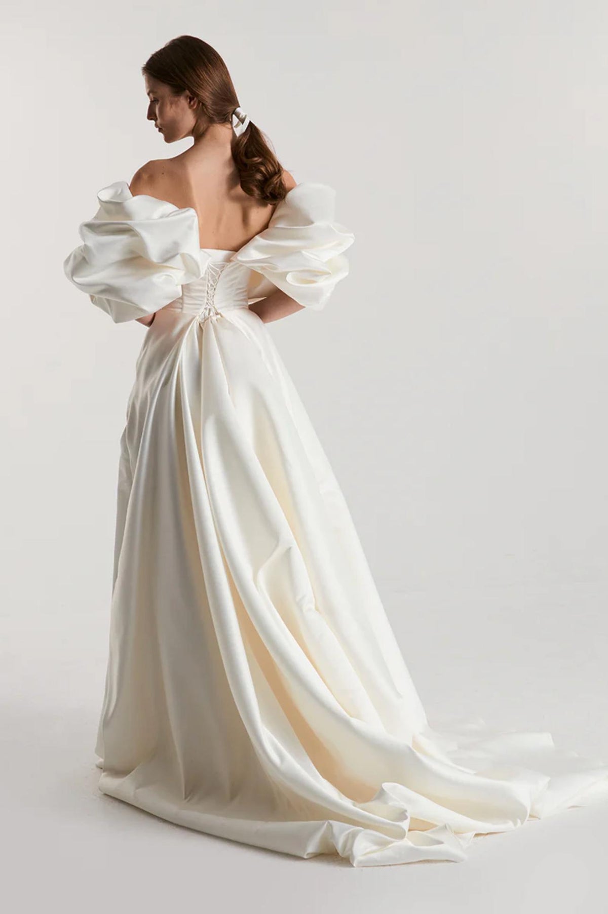 Off-shoulder white satin A-line gown with voluminous puffed sleeves and a lace-up corset back.