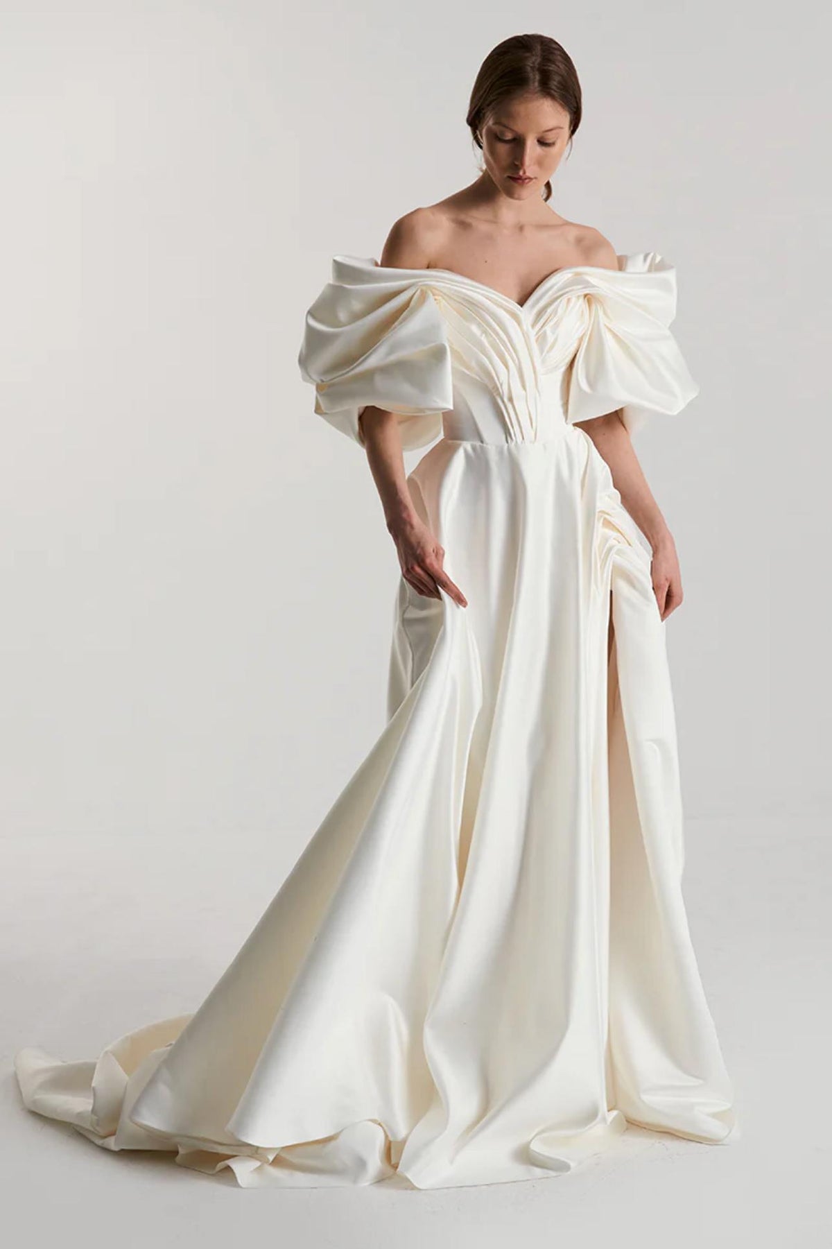 Off-shoulder white satin A-line gown with voluminous pleated sleeves and a high side slit for a formal look.