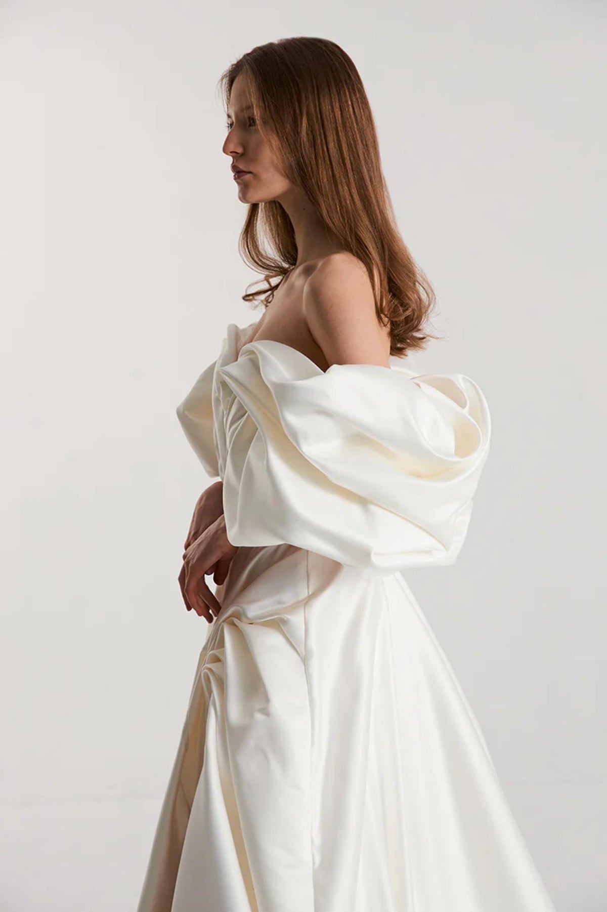 Off-shoulder white satin A-line gown with voluminous pleated sleeves and a high side slit for a vintage formal look.