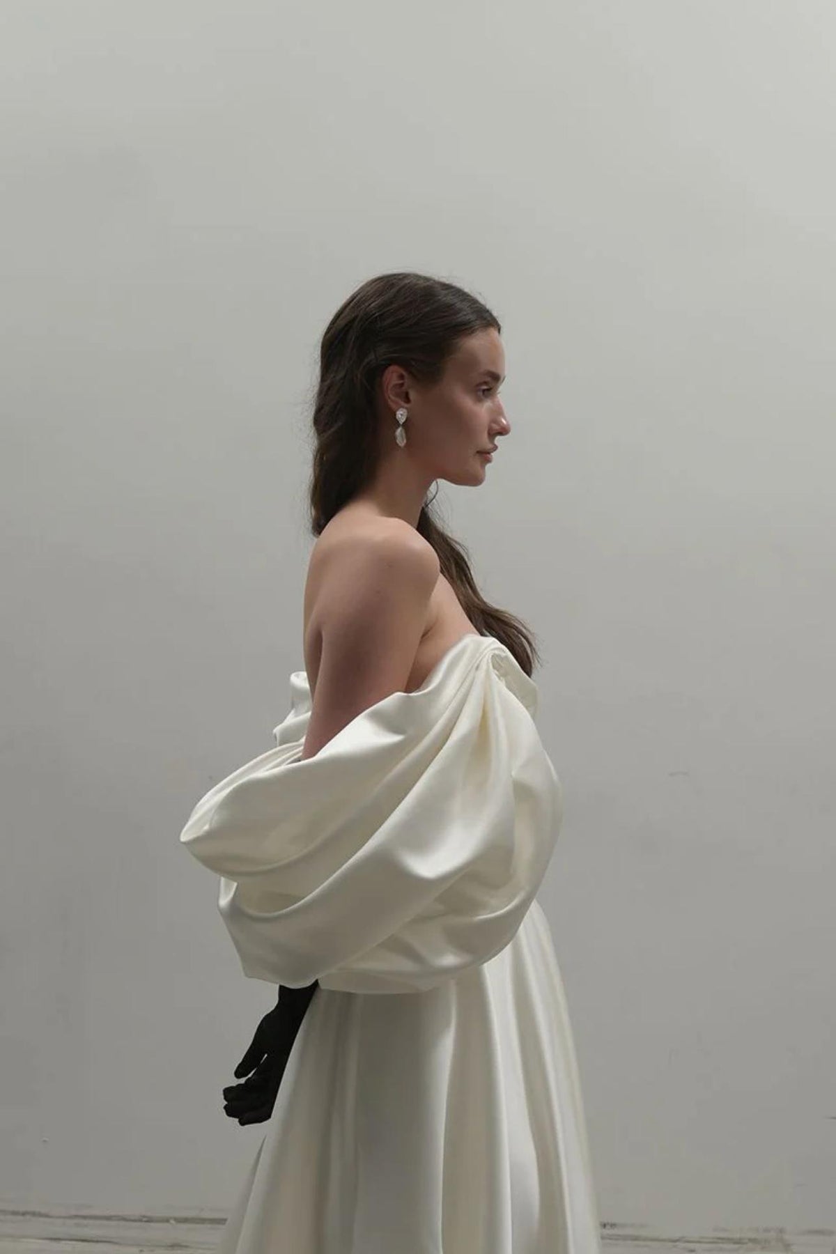 Off-shoulder ivory satin A-line gown with voluminous draped sleeves and a vintage-inspired silhouette.