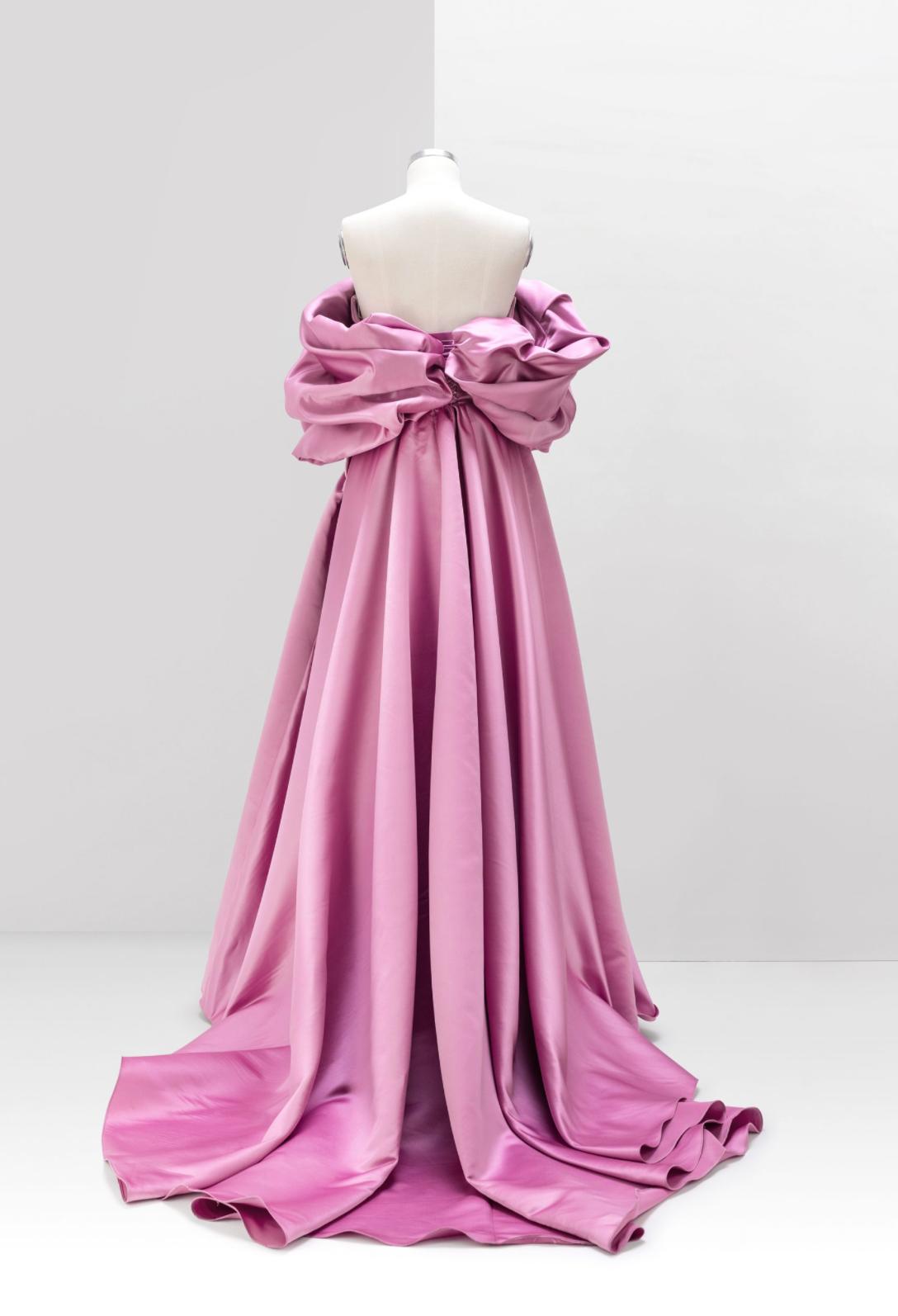 Pink off-shoulder A-line satin gown with voluminous pleated detailing and a sweeping floor-length train.
