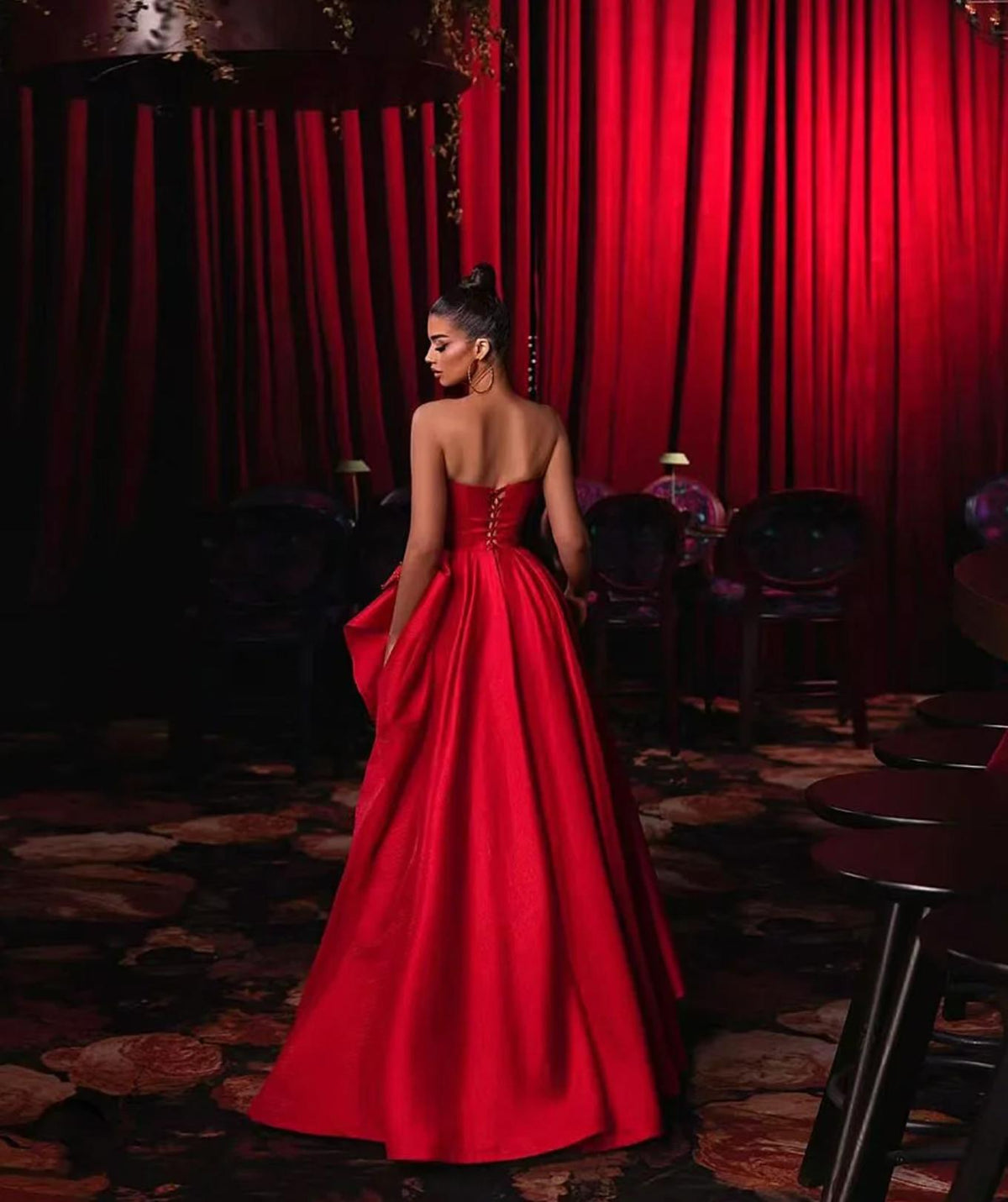 Red satin strapless A-line evening gown with a corset back and floor-length skirt in a formal setting.