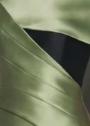 Close-up of the Faustini gown in sage green satin twill featuring a bold black contrast panel and structured pleating.