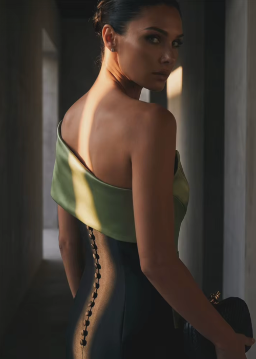 Model wearing a structured, two-tone satin twill gown with a green bodice, black skirt, and elegant button-back detail.