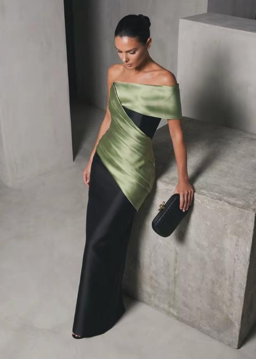 Model in a structured, off-the-shoulder sage green and black satin twill floor-length gown with a sleek, fitted silhouette.