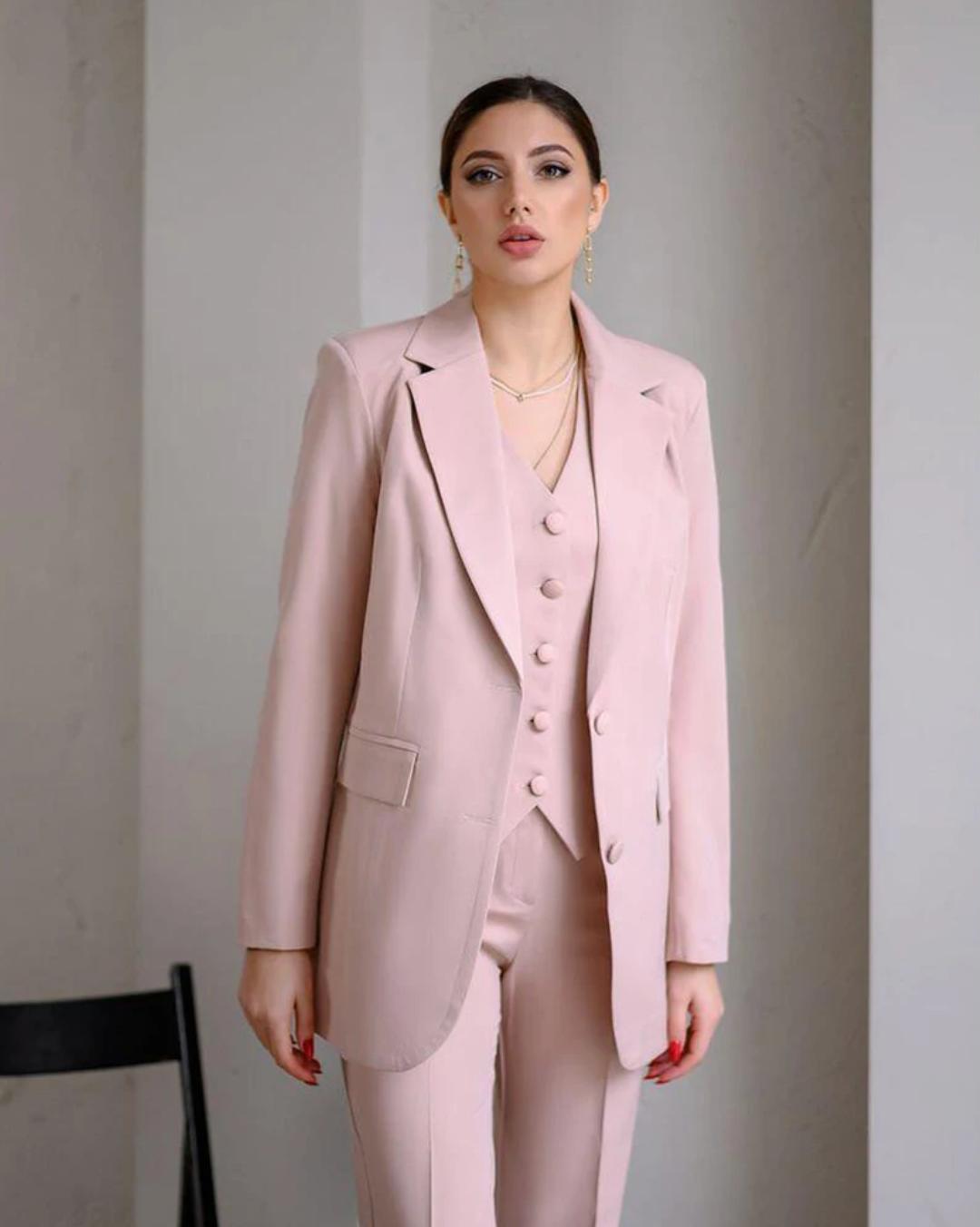 Woman wearing a pink three-piece serge suit featuring a single-breasted blazer, buttoned vest, and tailored trousers.