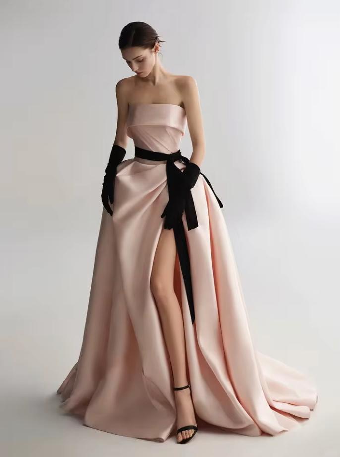 Strapless pale pink satin A-line ball gown with a high side slit, black ribbon waist tie, and matching black opera gloves.