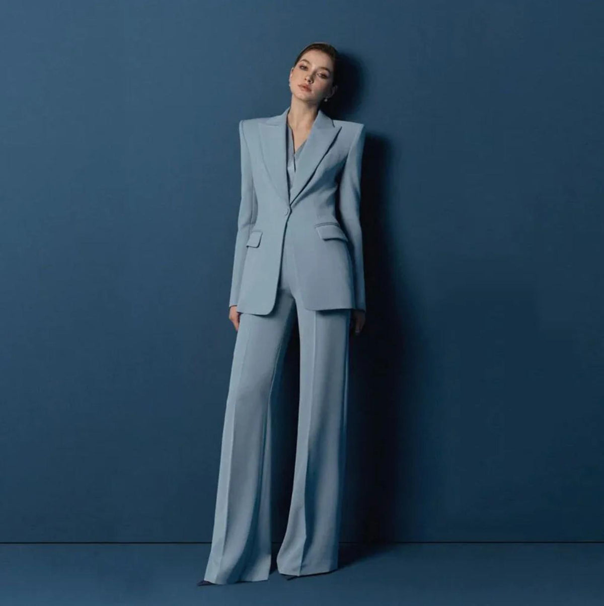 Woman wearing a light blue Italian satin suit with a structured one-button jacket and tailored wide-leg trousers.