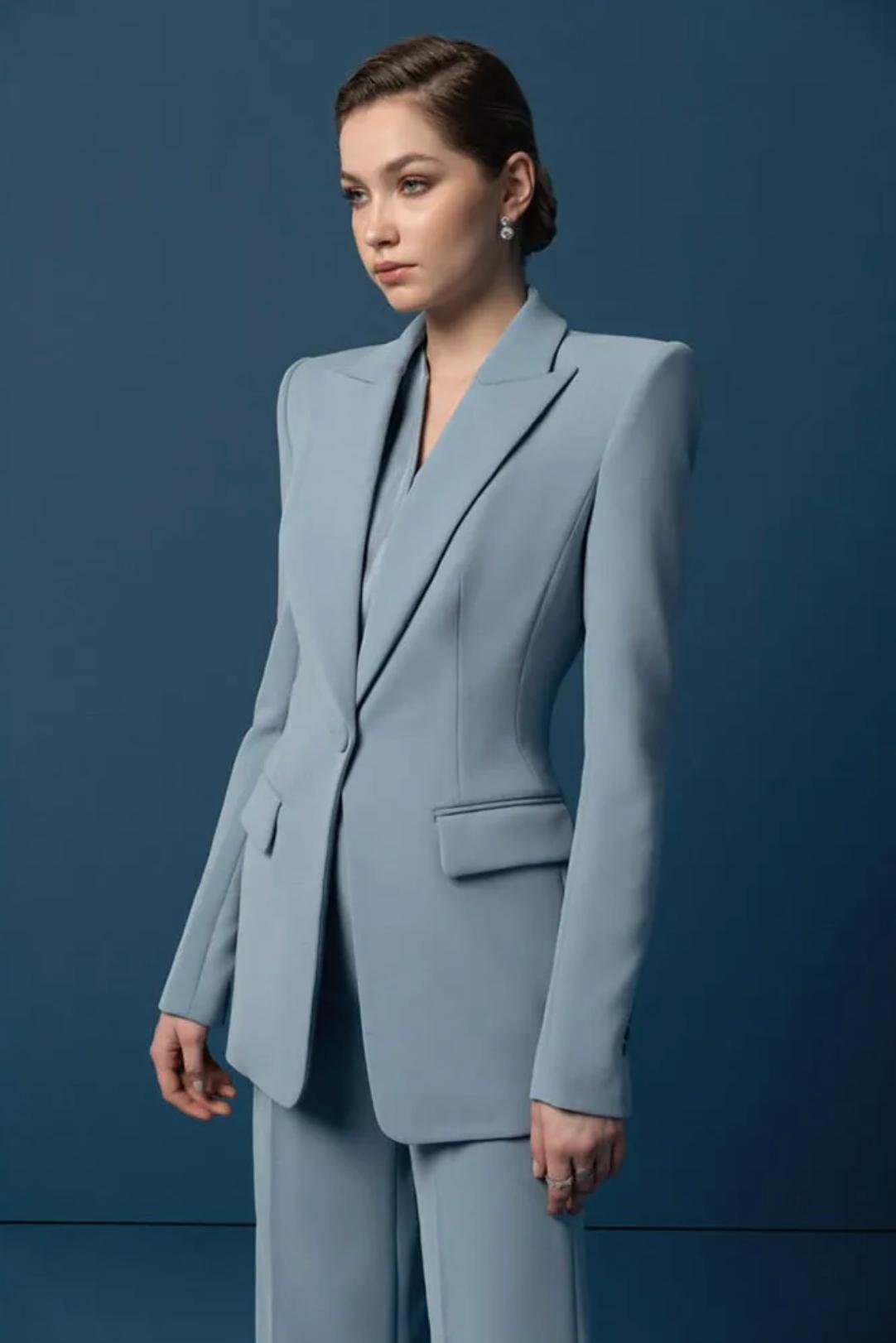 Woman wearing a structured, powder blue Italian satin suit set with a sleek one-button blazer and tailored trousers.