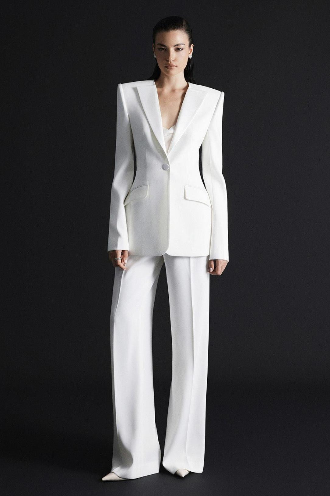 Woman wearing a white Italian satin suit set with a sharp one-button jacket and tailored wide-leg trousers.
