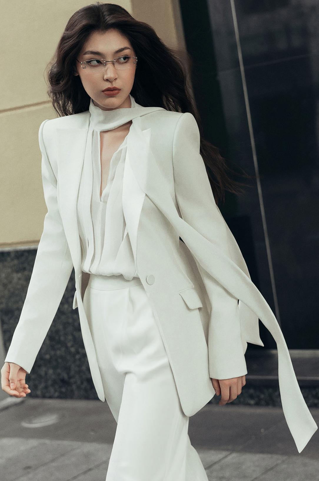 Woman wearing a sleek white Italian satin suit set with a one-button jacket and tailored trousers.