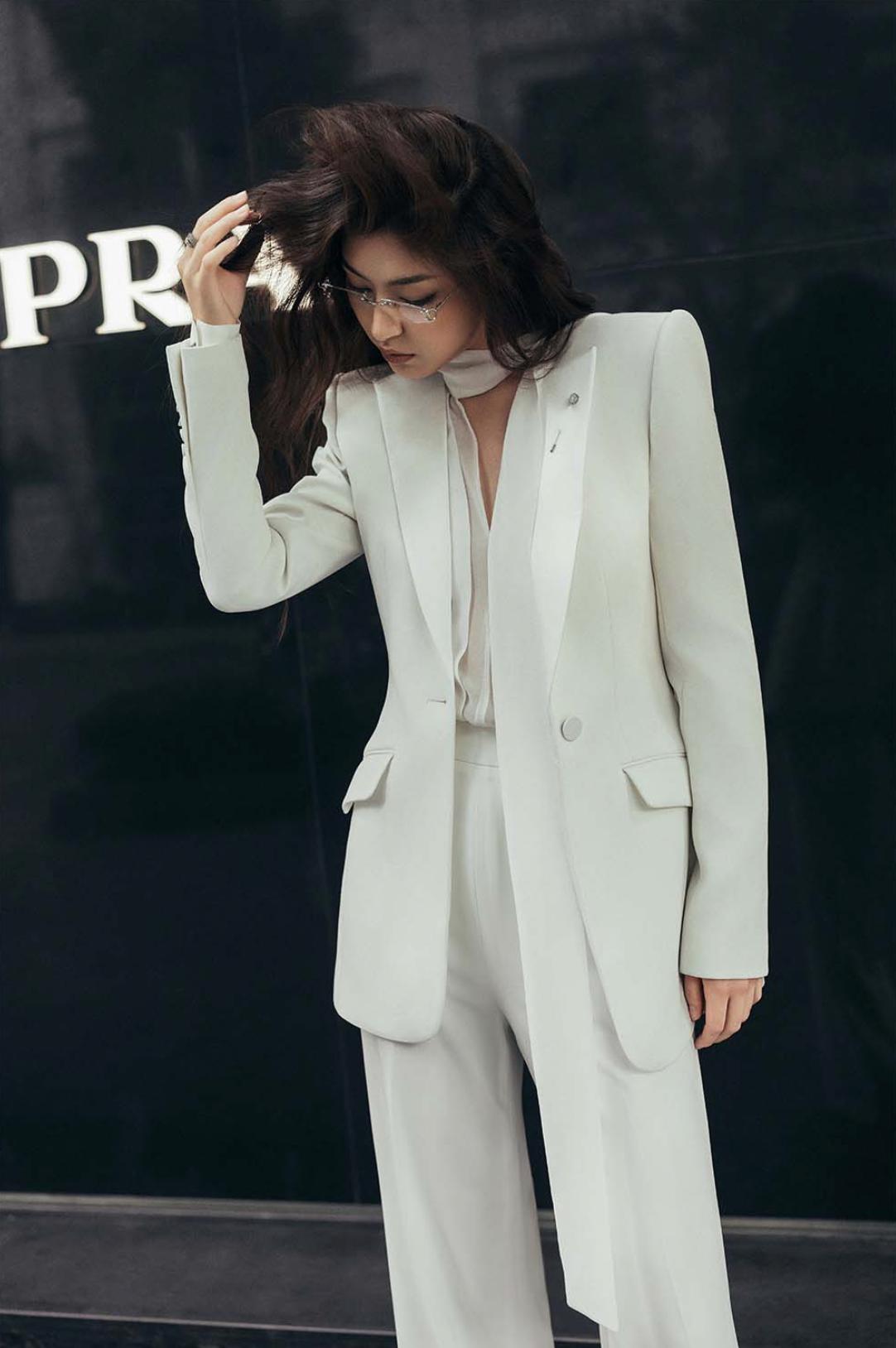 Woman wearing a sleek, cream-colored Italian satin suit set with a sharp one-button jacket and tailored trousers.
