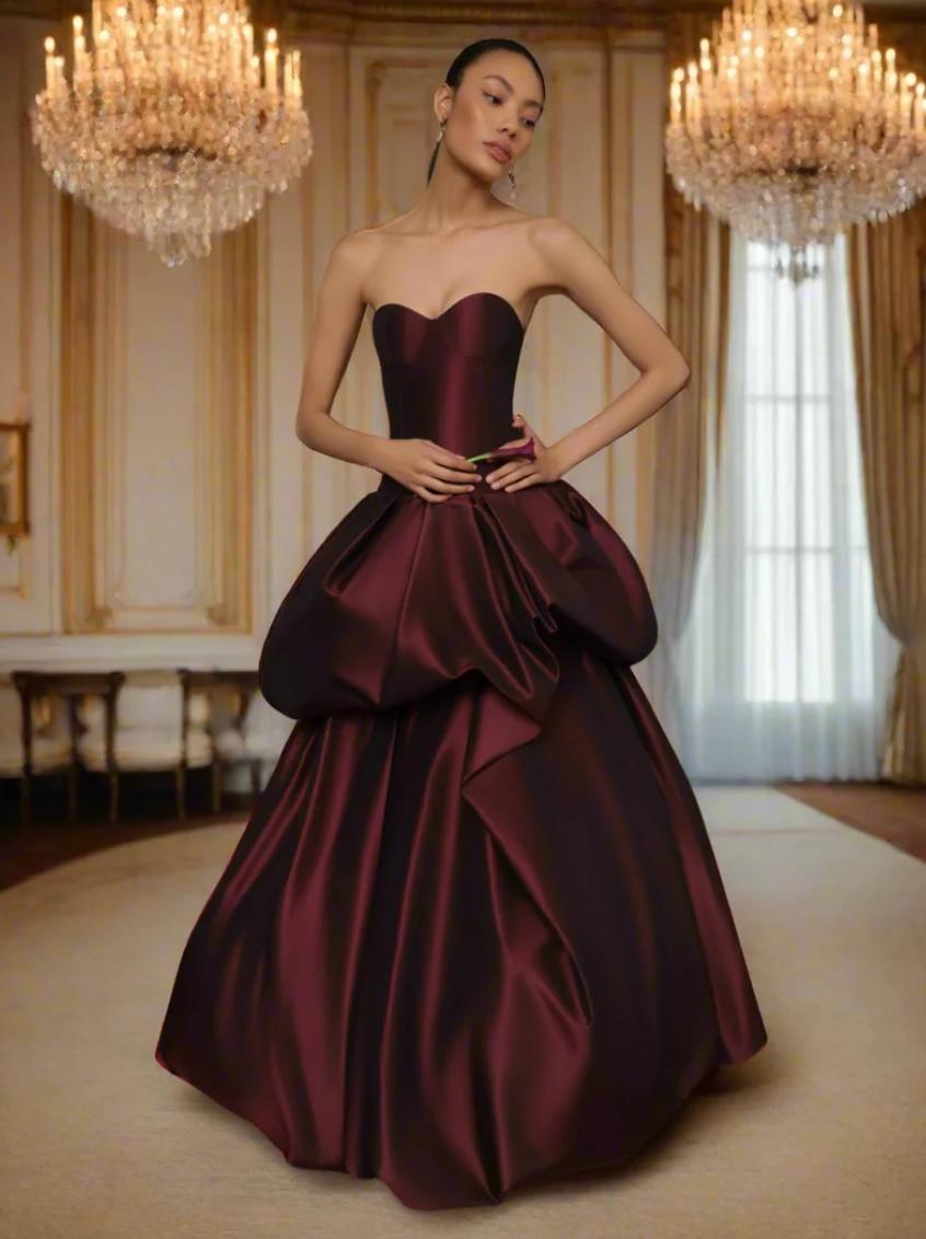 Burgundy strapless silk taffeta ball gown with a structured corset bodice and dramatic drop-waist tiered skirt.