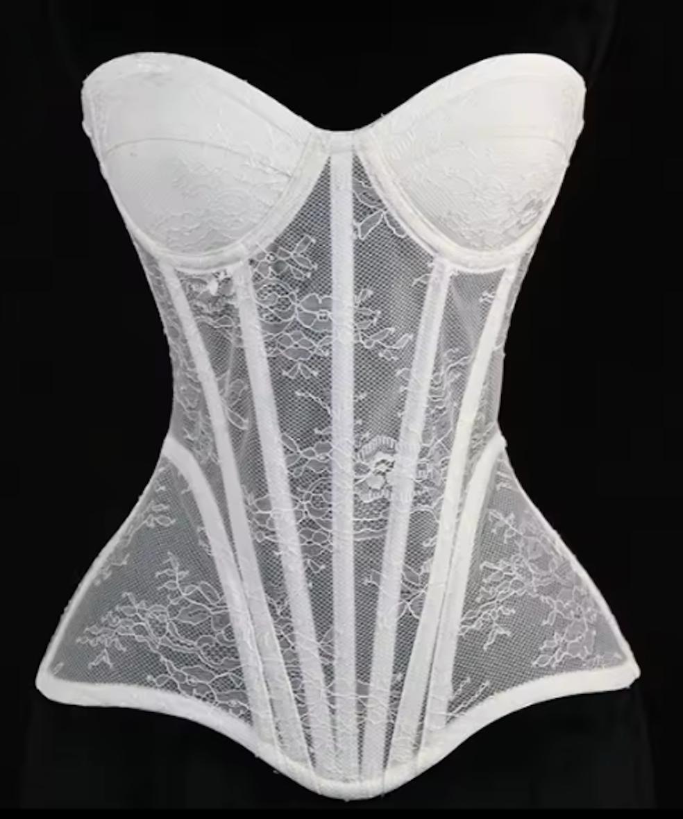 White Gia corset bustier featuring intricate lace detailing, steel-boned construction, and a sculpted waist silhouette.