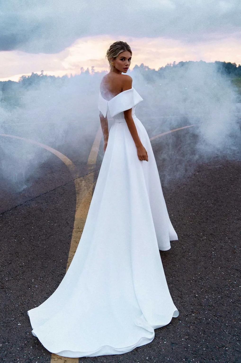 White satin Grand Cayman mermaid gown with an off-shoulder sweetheart neckline and a dramatic detachable skirt.
