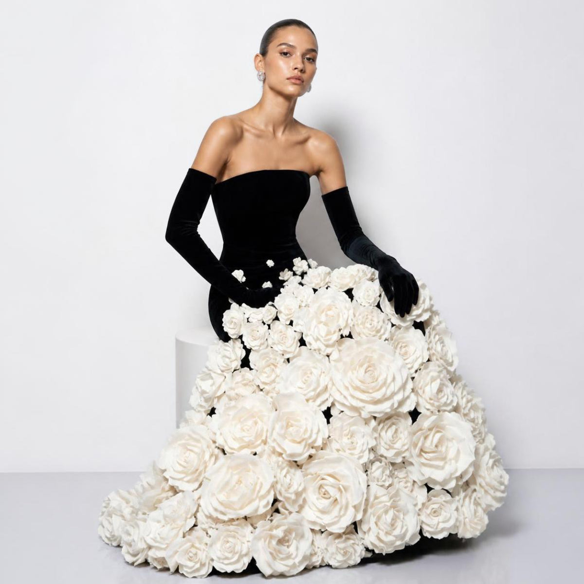Strapless black velvet evening gown featuring a voluminous skirt covered in handmade white 3D taffeta floral appliqués.