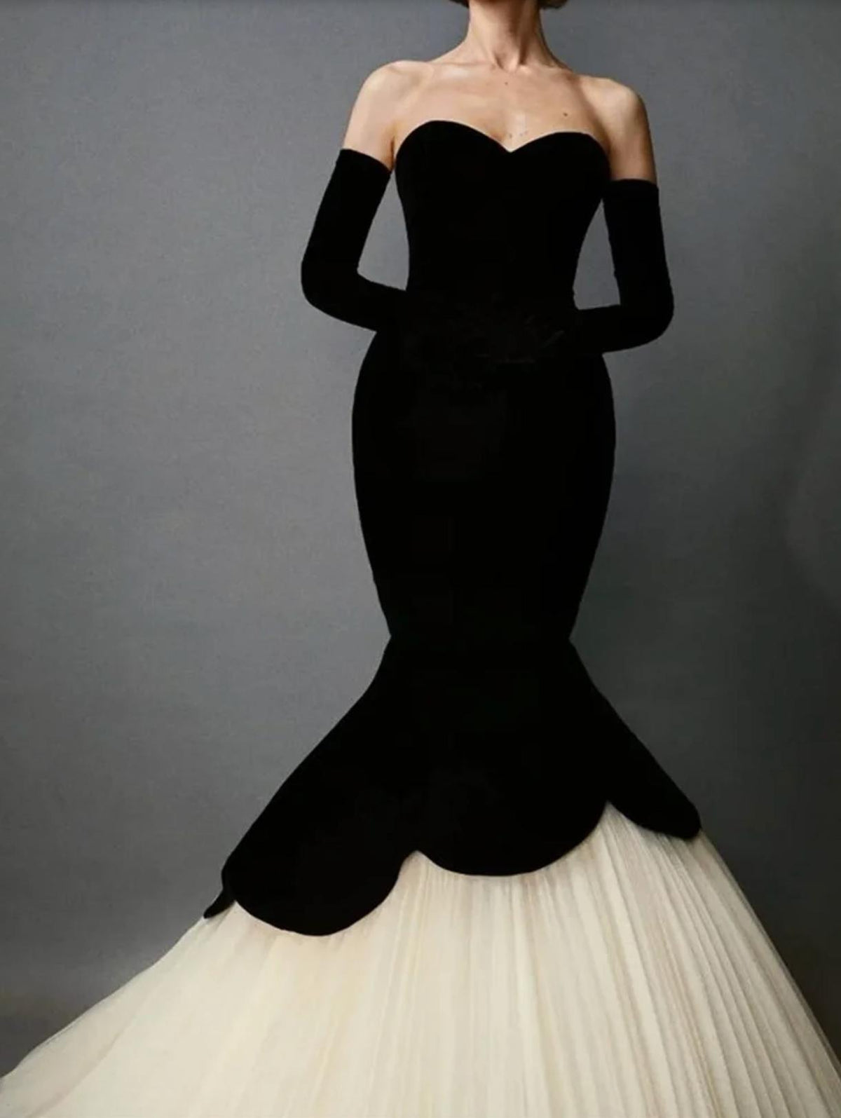 Black velvet fishtail gown with a sweetheart neckline, matching opera gloves, and a voluminous cream tulle skirt.