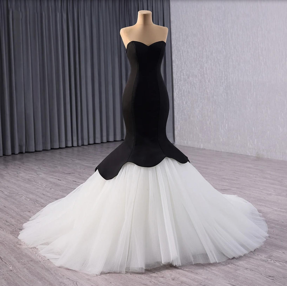 Black velvet fishtail gown with a sweetheart neckline and voluminous white tulle skirt on a mannequin.