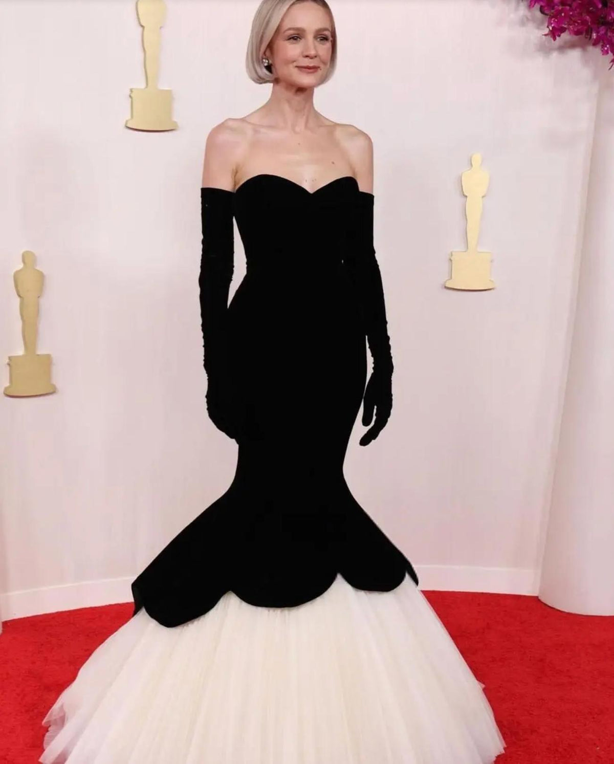 Black velvet fishtail gown with a strapless bodice, matching opera gloves, and a voluminous white tulle hem.