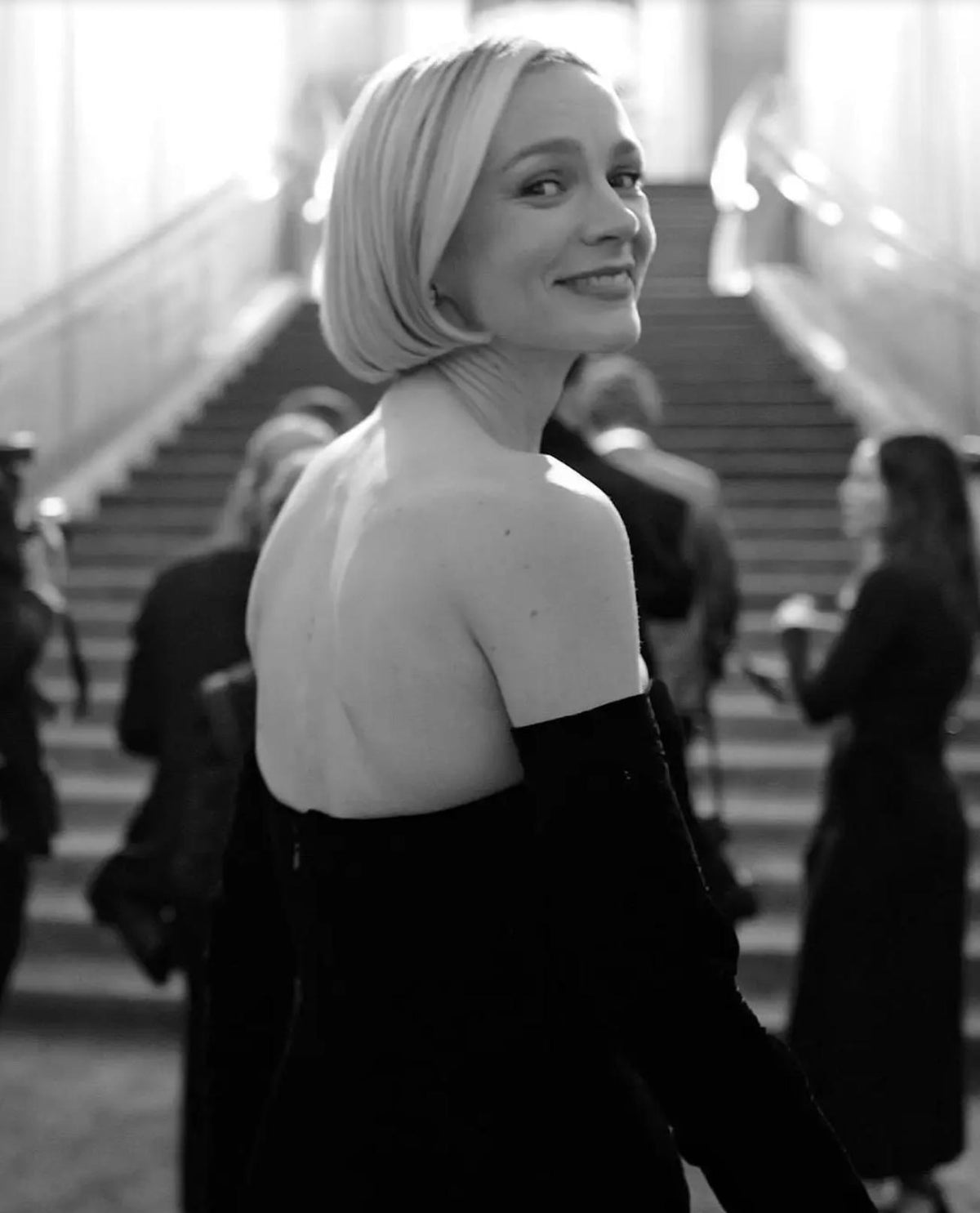 Woman in a black velvet Hepburn Audrey gown with matching opera gloves, captured in a stylish black and white portrait.