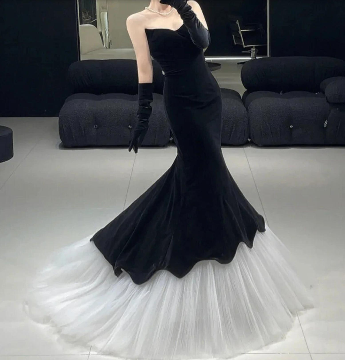 Black velvet fishtail gown with a voluminous white tulle hem, sleeveless bodice, and matching opera-length gloves.