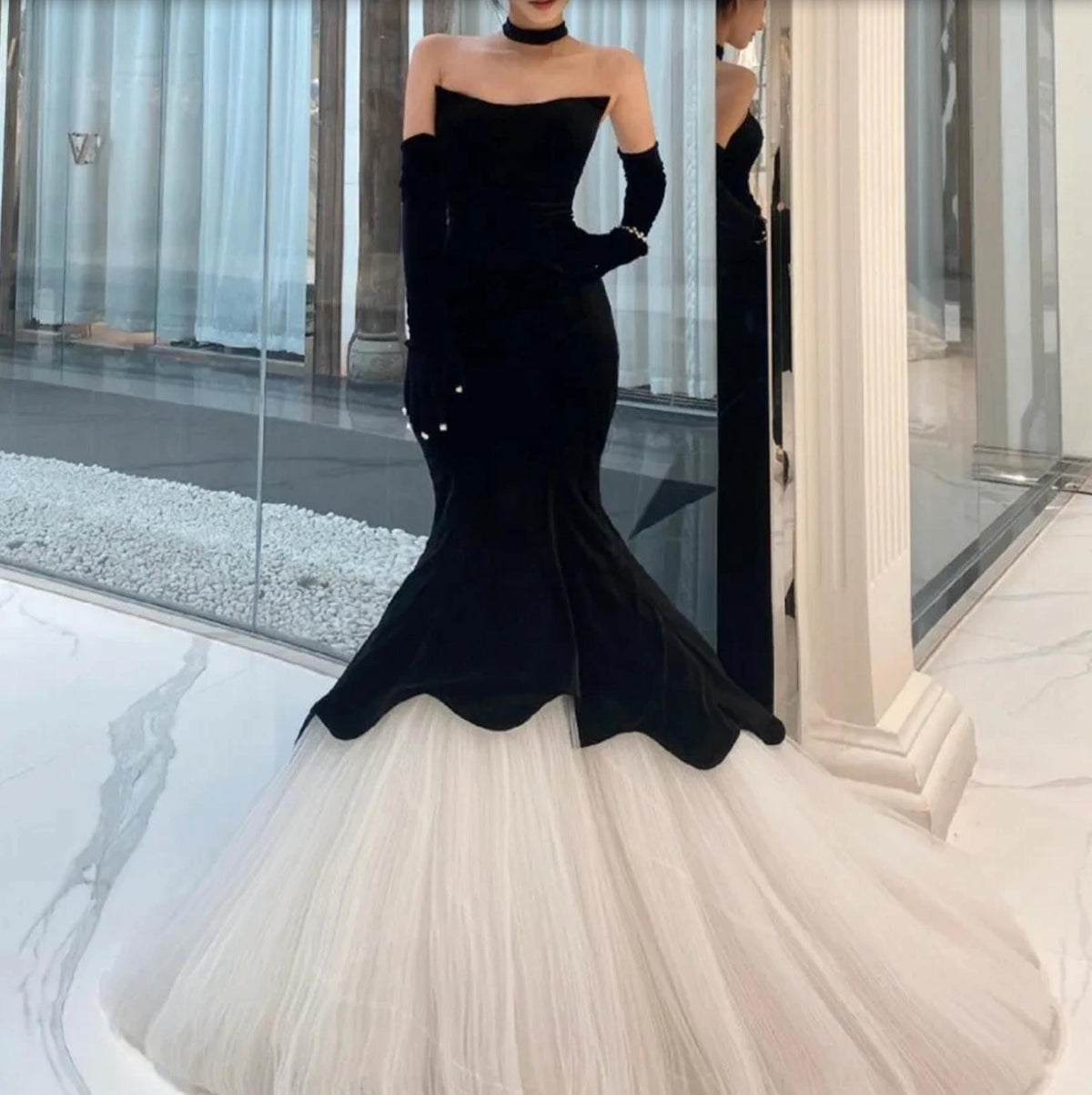 Black velvet fishtail gown with a white tulle skirt, strapless bodice, and matching opera gloves.