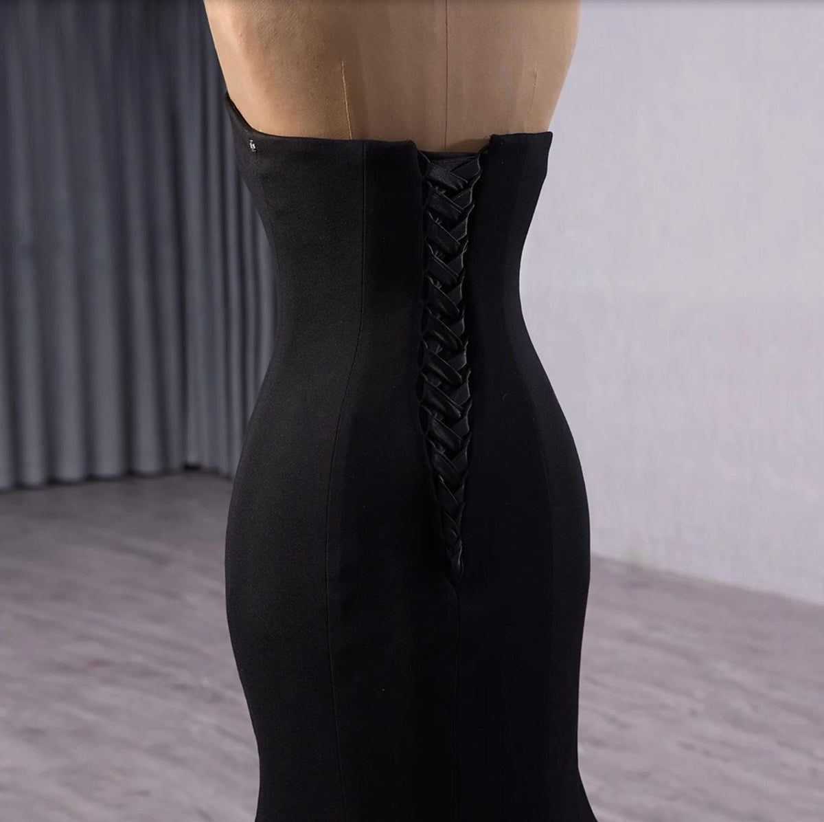 Black velvet fishtail gown featuring a structured bodice with a detailed lace-up corset back closure.