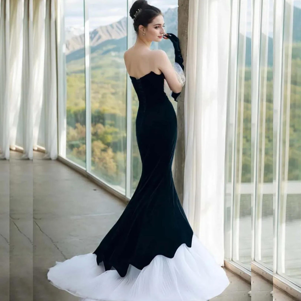 Sleeveless black velvet fishtail gown with a white tulle hem, lace-up back, and matching gloves.