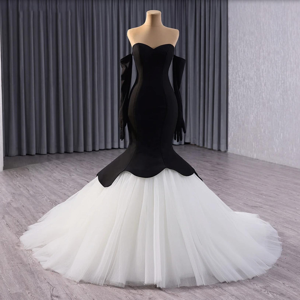 Black and white fishtail gown with a sweetheart neckline, tulle skirt, and matching opera gloves on a mannequin.