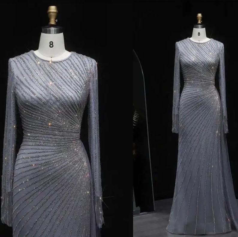 Grey floor-length evening gown with long sheer sleeves, intricate diagonal beading, and a fitted silhouette on a mannequin.