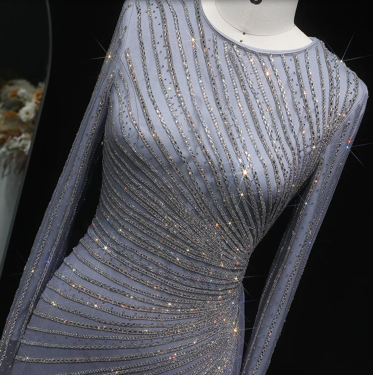 Grey Historia del Tango evening gown with long sheer sleeves, intricate silver beading, and a sparkling o-neck design.