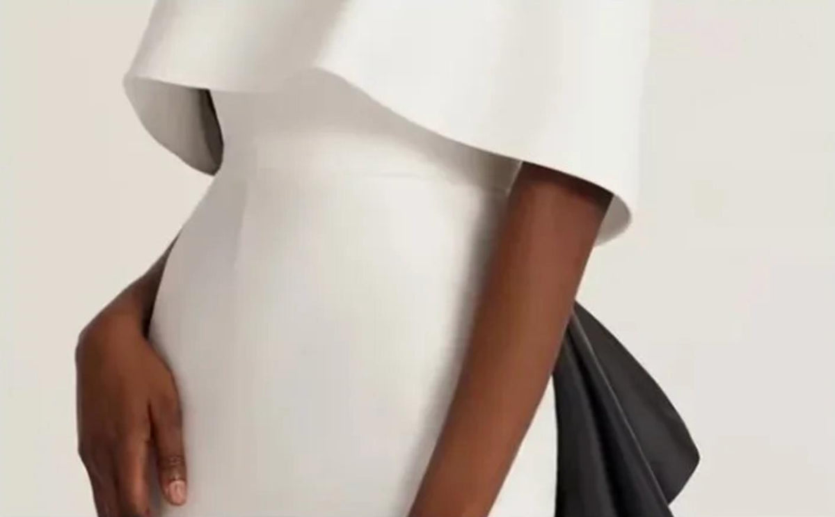 Elegant white off-shoulder Hvar gown in smooth satin with a dramatic black train and fitted trumpet silhouette.
