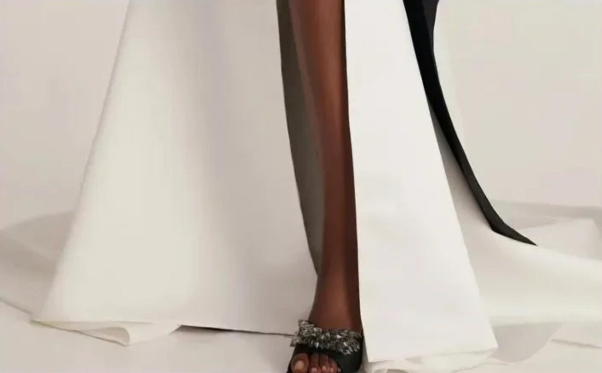 Close-up of a floor-length white satin trumpet gown with a high leg slit and sweeping train.