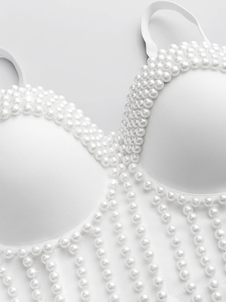 White Ina corset camisole featuring intricate pearl bead embellishments and decorative fringe detailing.