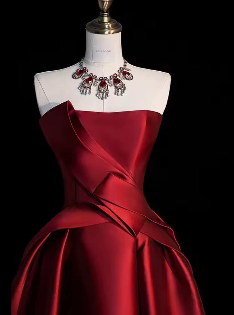 Strapless red satin midi dress with a structured corset bodice and pleated A-line skirt on a mannequin.