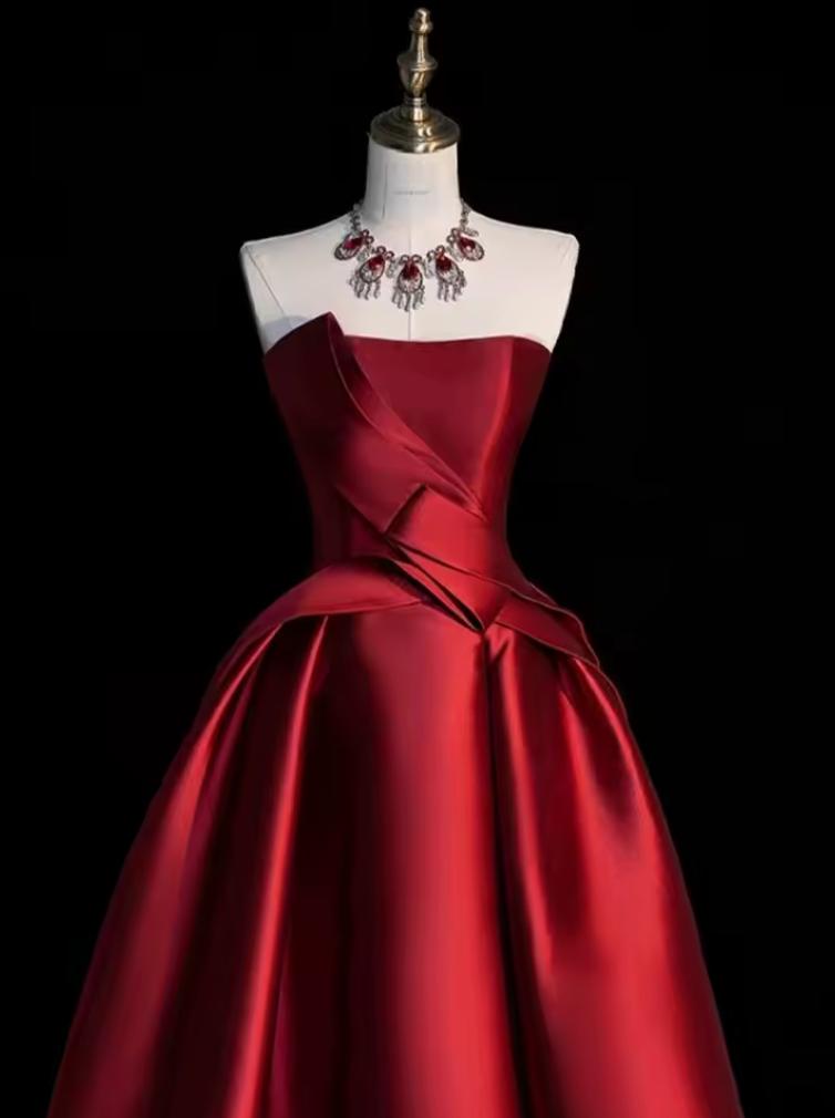 Strapless red satin midi dress with a structured corset bodice and pleated A-line skirt on a mannequin.