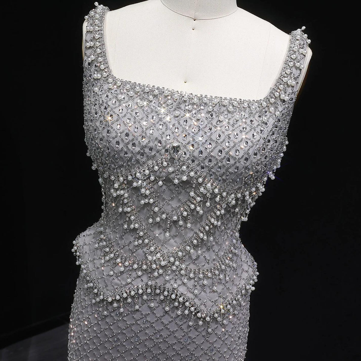 Ivar mermaid gown with a square neckline, featuring intricate silver beading and shimmering crystal embellishments.