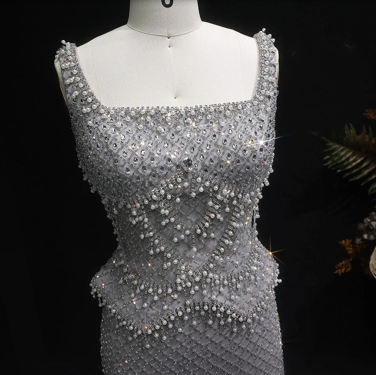 Ivar mermaid gown with a square neckline, featuring intricate silver beading and shimmering crystal embellishments.