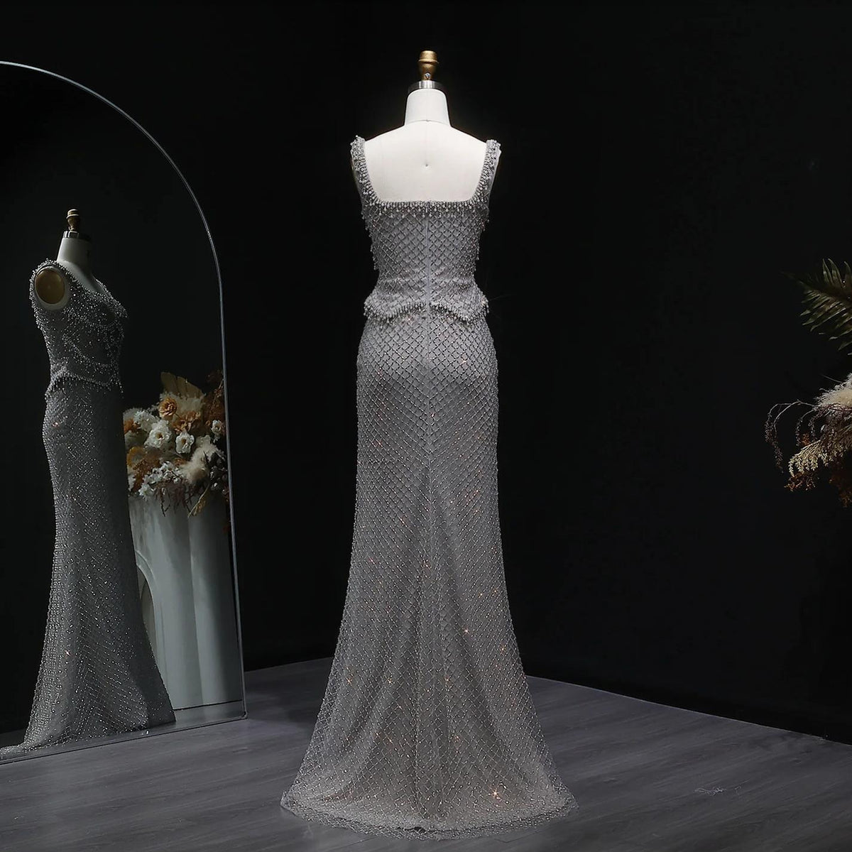 Silver mermaid-style Ivar gown with a square neckline, delicate straps, and intricate crystal beading on a mannequin.