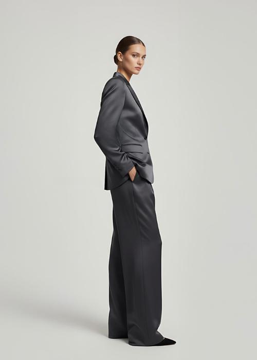 Model wearing a dark gray satin pantsuit with a single-breasted blazer and wide-leg trousers against a neutral background.