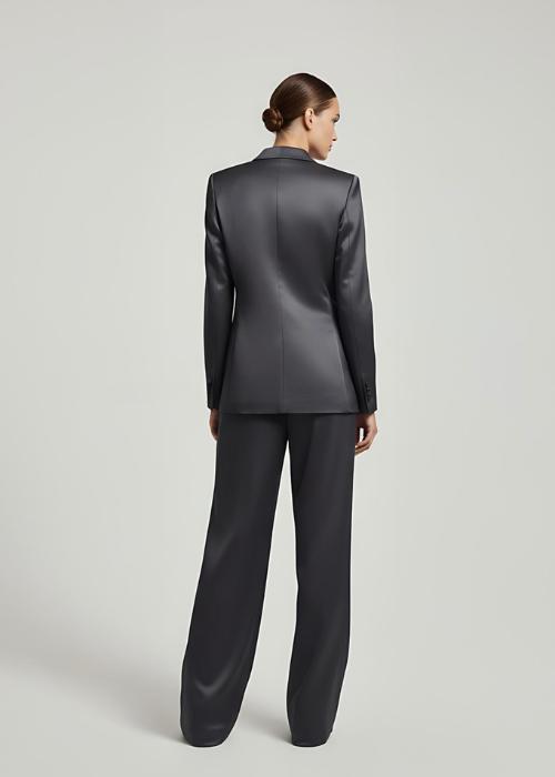 Woman wearing a dark gray satin pantsuit with a tailored single-breasted blazer and wide-leg trousers.
