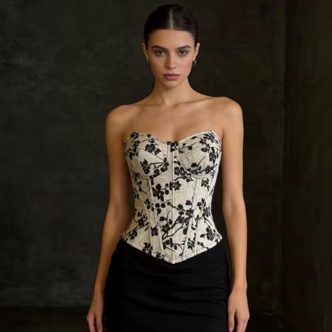 Model wearing a strapless, structured Ivy bustier corset with a cream and black floral print and sweetheart neckline.